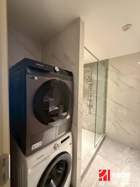 Badezimmer in einer 3-Zimmer-Wohnung mit Waschmaschine und Trockner neben der Duschkabine.