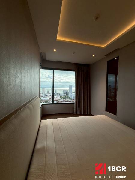 Schlafzimmer in einer 3-Zimmer-Wohnung mit Blick auf die Stadt durch ein großes Fenster.