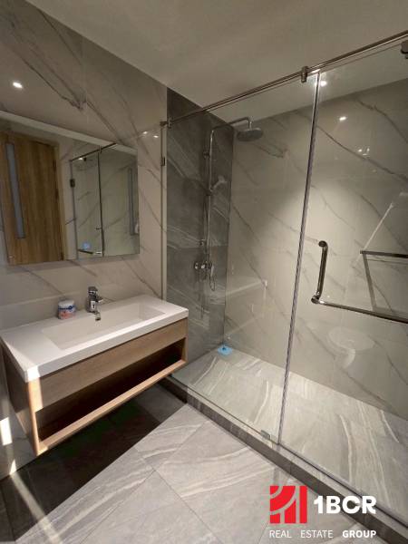 Badezimmer in einer 3-Zimmer-Wohnung mit einem großen Spiegel und einer Duschkabine mit Glaswand.