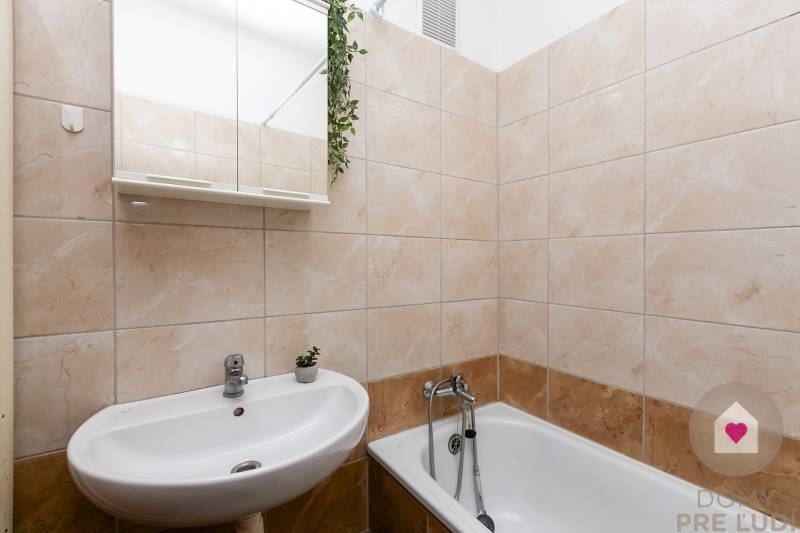 Badezimmer mit Badewanne, Waschbecken und Spiegel in einer Einzimmerwohnung.