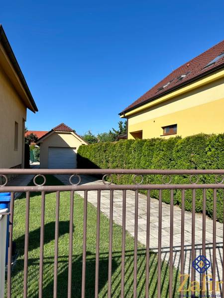 Ein Haus mit Garage in der Bradlanská-Straße in Trnava, umgeben von Rasen und einem Zaun.
