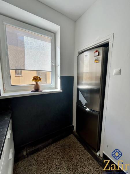 Küche einer 3-Zimmer-Wohnung mit Kühlschrank und Fenster mit Jalousie.