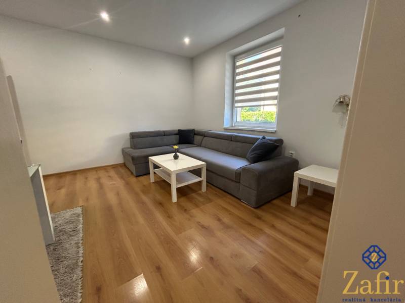 Wohnzimmer in einer 3-Zimmer-Wohnung mit Holzboden und grauem Sofa.