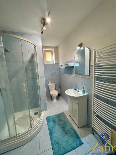 Badezimmer in einer 3-Zimmer-Wohnung mit blauen Fliesen, einer Duschkabine und einem Waschbecken.