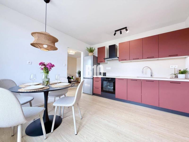 Küche in einer 3-Zimmer-Wohnung mit Esstisch, bunten Schränken und Leuchte.