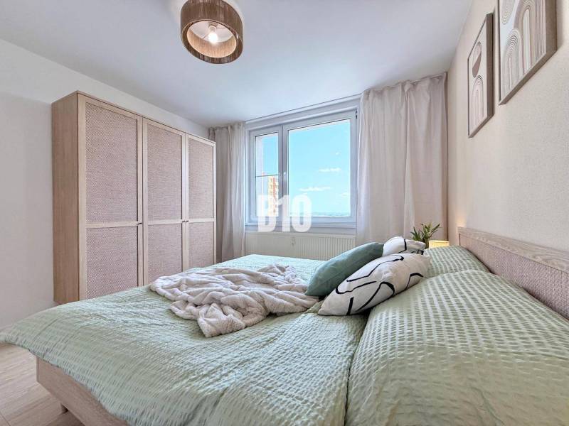 Helles Schlafzimmer in einer 3-Zimmer-Wohnung mit großem Bett, Kleiderschrank und Fenster.