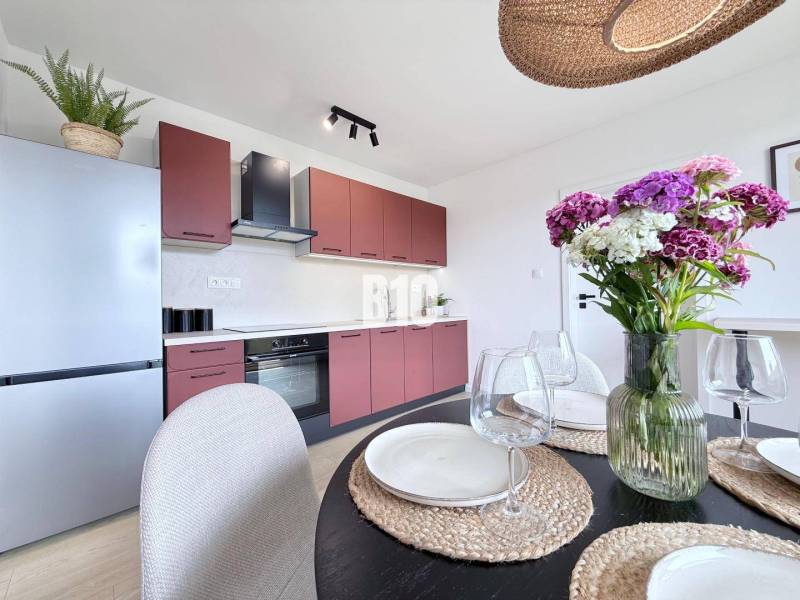 Küche in einer 3-Zimmer-Wohnung mit Tisch, Blumen und moderner Ausstattung.
