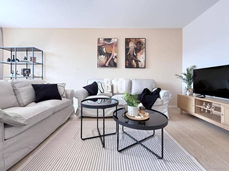 Helles Wohnzimmer mit Sofas, dekorativen Bildern und einem Tisch in einer 3-Zimmer-Wohnung.
