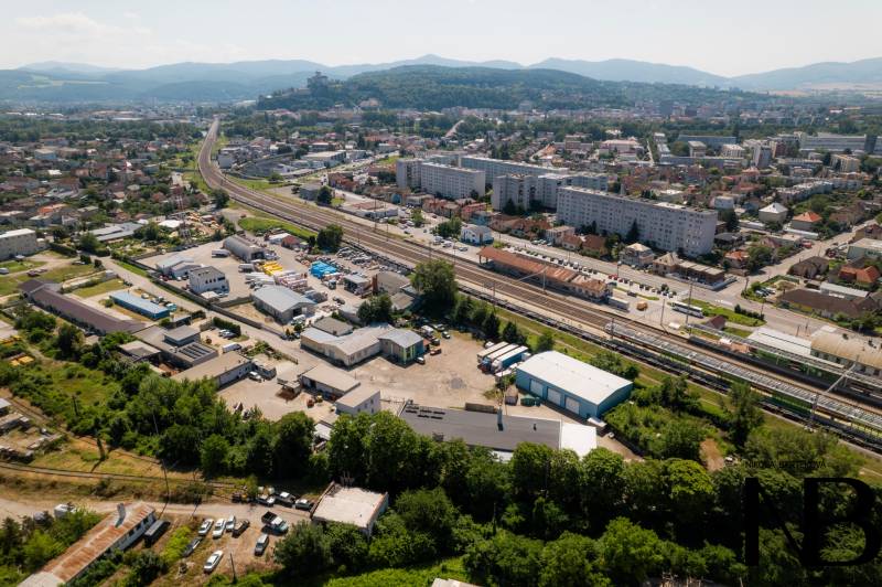 Luftaufnahme von Trenčín, Kasárenská-Straße und Lagerhallen, im Hintergrund Berge.