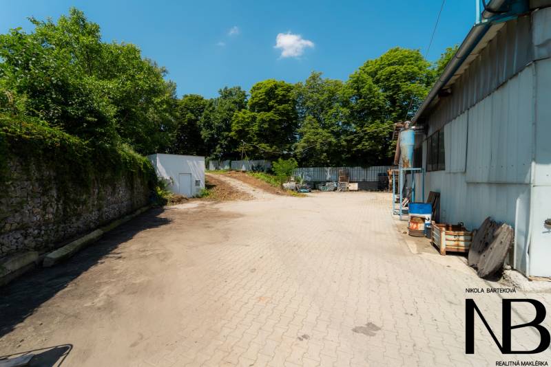 Gepflasterte Fläche bei der Lagerhalle in der Kasárenská-Straße in Trenčín, umgeben von Grünflächen.