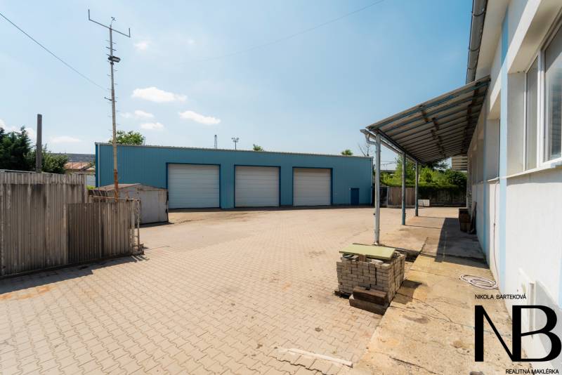 Lager und Hallen in der Kasárenská-Straße in Trenčín mit befestigter Fläche und blauem Gebäude.