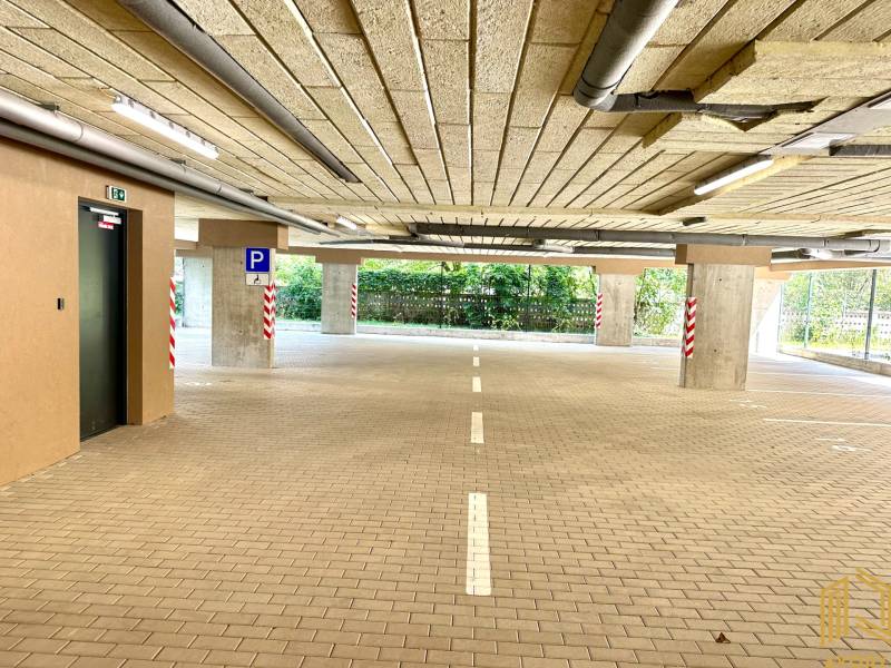 Parkhaus mit barrierefreiem Zugang, beleuchtet und mit markierten Parkplätzen.