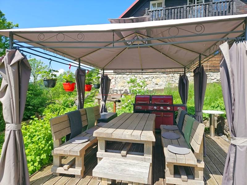 Einfamilienhaus in Donovaly mit Terrasse und Unterstand, neben einer gemauerten Mauer.