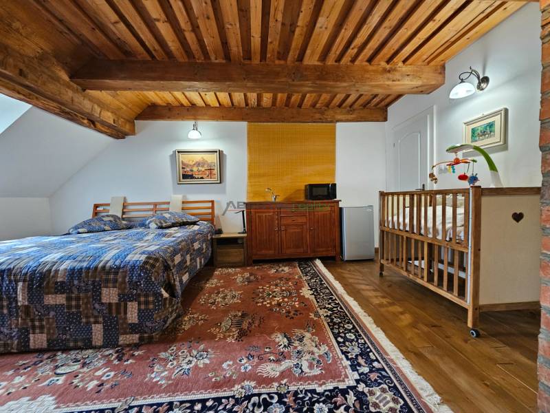 Schlafzimmer in einem Einfamilienhaus mit Holzdecke, Bett, Kinderbett und Teppich.