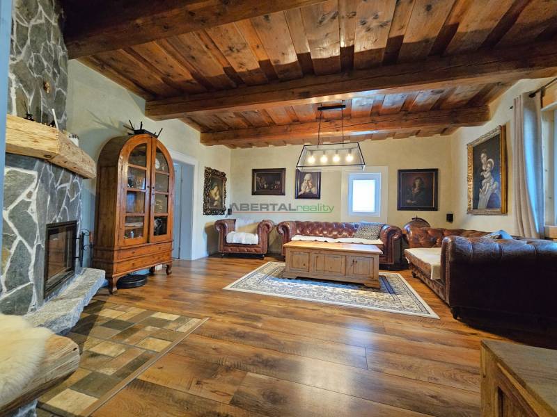 Wohnzimmer in einem Einfamilienhaus mit Kamin, Holzbalkendecke und bequemen Sofas.