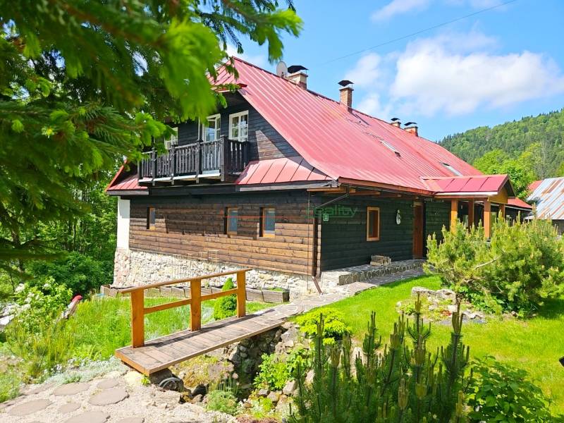 Ein Einfamilienhaus in Donovaly mit einer Holzfassade und einem roten Dach in einer natürlichen Umgebung.