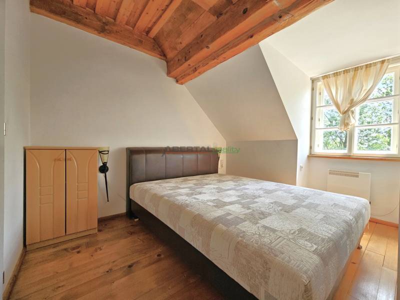 Ein Schlafzimmer im Dachgeschoss eines Einfamilienhauses mit Dachbalken und einem großen Fenster.
