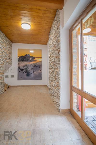 Der Flur des Ferienapartments mit steinverkleideten Wänden und einem Bild von Bergen.