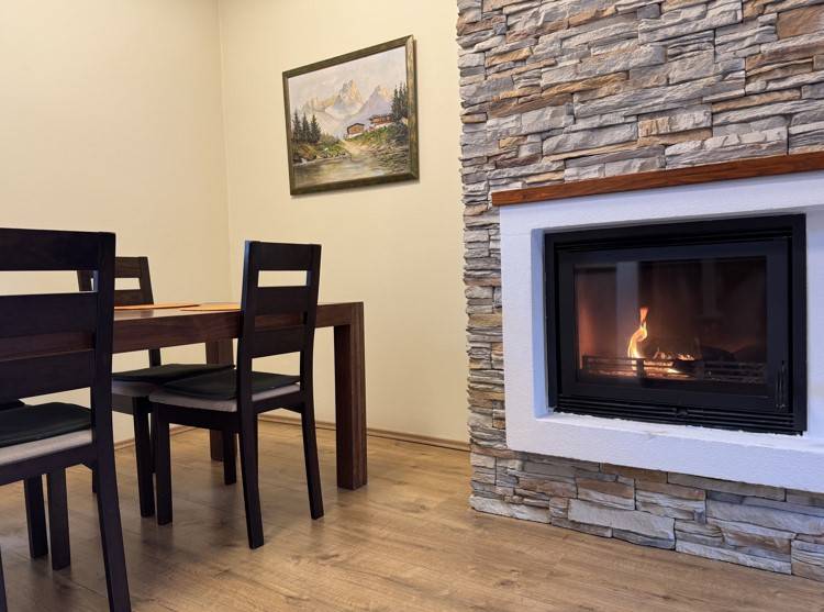 Kamin in der Ferienwohnung, mit Holztisch und Bild an der Wand.
