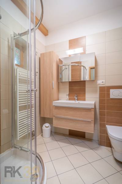Badezimmer in einer Ferienwohnung mit Holzmöbeln und Duschkabine.