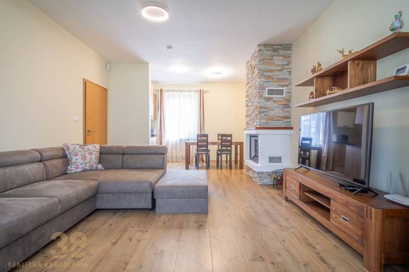 Wohnzimmer in einer Ferienwohnung mit Kamin und bequemer Couch.
