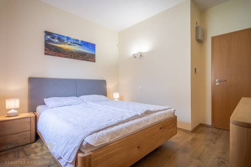 Helles Schlafzimmer des Ferienapartments mit Doppelbett, Nachttischen und Wanddekoration.
