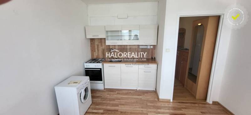 Küche in einer Einzimmerwohnung mit Herd, Geschirrspüler und Schränken, Holzboden.