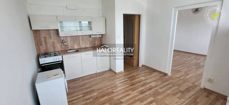 Küchenzeile in einer Einzimmerwohnung mit Holzboden und weißen Schränken.