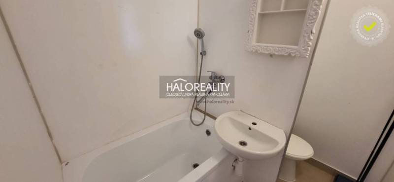 Badezimmer in einer Einzimmerwohnung mit Badewanne, Spiegel und Waschbecken.