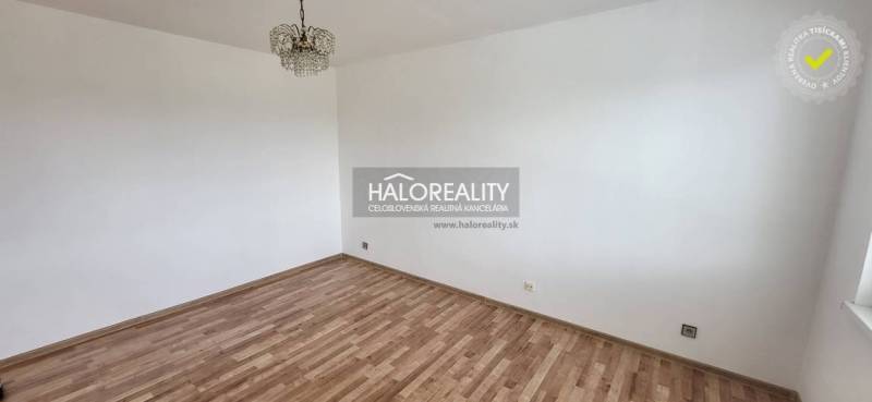 Ein leerer Raum in einer Einzimmerwohnung mit Parkettboden und Deckenleuchte.