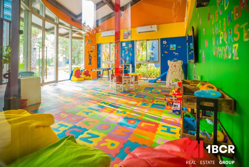Ein farbenfroher Indoor-Spielplatz im Inneren eines Wohnbauprojekts mit Spielzeug und Tischen.