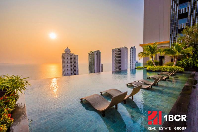 Schwimmbad, Liegestühle und Panorama des Wohnungsbaus in Pattaya bei Sonnenuntergang.