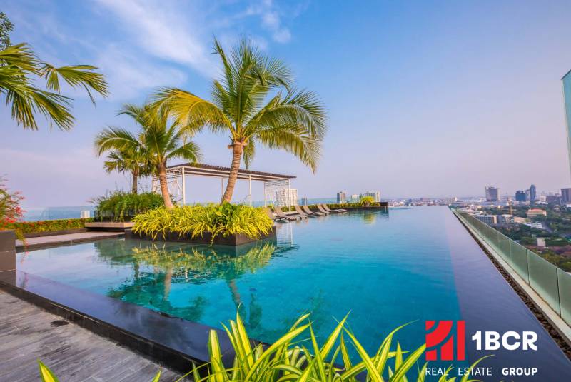 Infinity-Pool und Palmen auf dem Dach mit Blick auf die Skyline von Pattaya, Wohnungsbau.