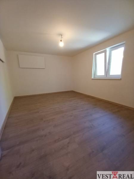 Ein leerer Raum mit Laminatboden und weißen Wänden in einem Einfamilienhaus.