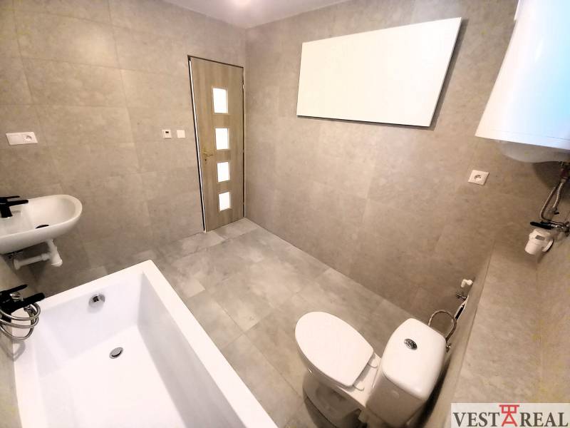 Badezimmer im Einfamilienhaus mit Badewanne, Waschbecken und Toilette, helle Fliesen.