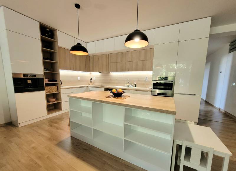 Küche in einer 3-Zimmer-Wohnung mit Insel, Holzelementen und eingebauten Geräten.