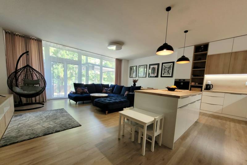 Wohnzimmer in einer 3-Zimmer-Wohnung mit Kücheninsel, Sofa und Schaukel.