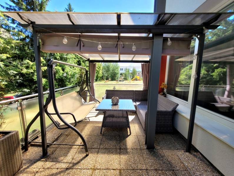 Die Terrasse einer 3-Zimmer-Wohnung in Banská Bystrica mit einer Schaukel und einem Tisch zum Sitzen.
