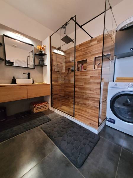 Badezimmer in einer 3-Zimmer-Wohnung mit Holzdusche und Waschmaschine.