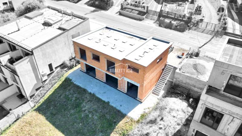 Unvollendetes Einfamilienhaus in Trnové, Žilina, umgeben von einem grünen Grundstück und benachbarten Häusern.