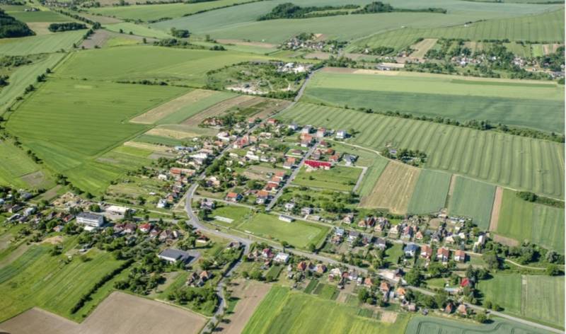Luftaufnahme eines Dorfes zwischen Feldern in Kamenné Kosihy, ideal für Gewerbegrundstücke.