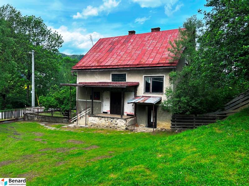 Ein Einfamilienhaus in Veľká Lesná mit rotem Dach und einem Garten, umgeben von Grün.