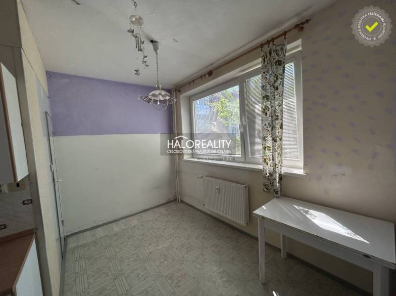 Ein Zimmer in einer Einzimmerwohnung mit einer lila Wand und einem weißen Tisch unter dem Fenster.