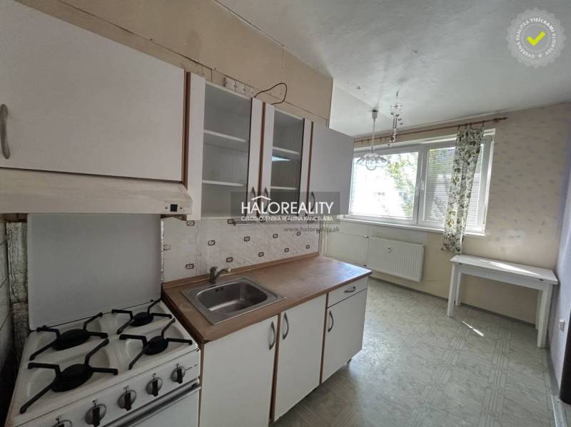 Küche mit Herd und Spüle in einer Einzimmerwohnung, helle Einrichtung, großes Fenster.