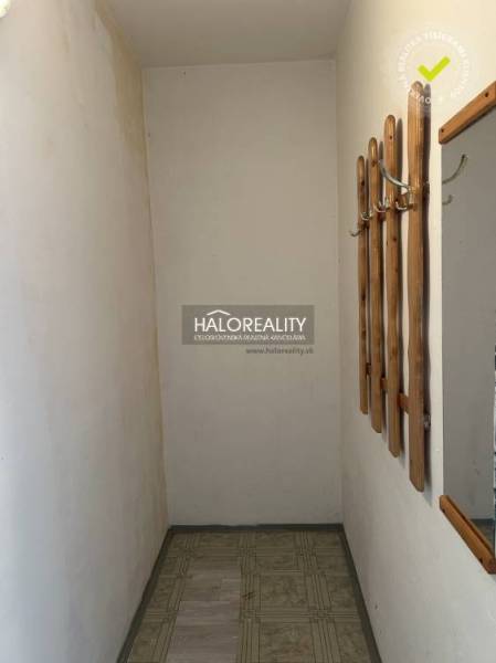 Ein schmaler Flur in einer Einzimmerwohnung mit einer hölzernen Garderobe an der Wand.
