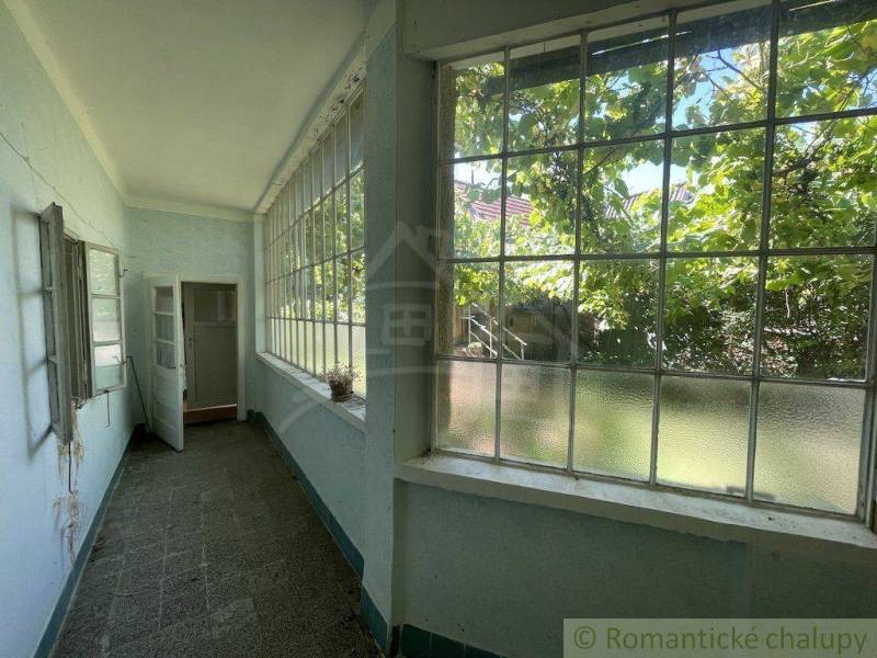 Helle Veranda eines Einfamilienhauses mit großen Fenstern und Blick auf den Garten.