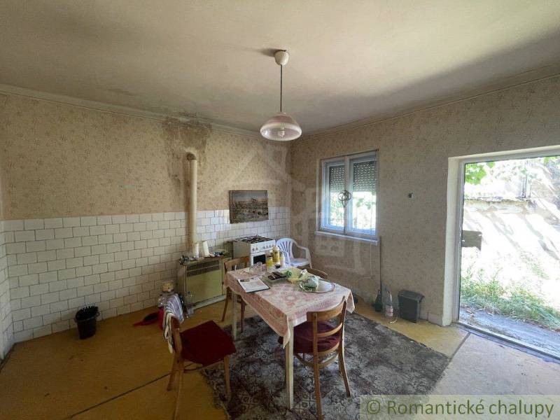 Innenraum eines Einfamilienhauses mit älteren Möbeln, Küchentisch und offenen Türen zum Garten.