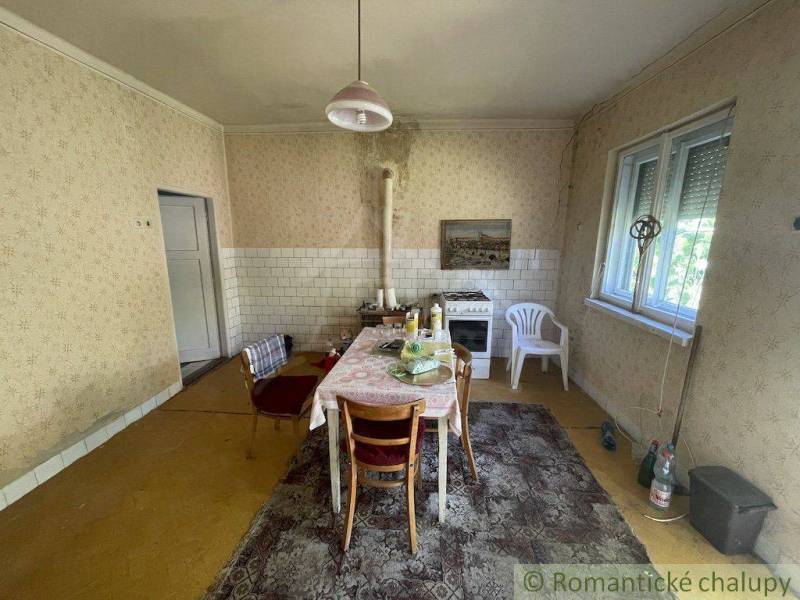 Küche in einem Einfamilienhaus mit Esstisch, älterem Herd und einfacher Einrichtung.