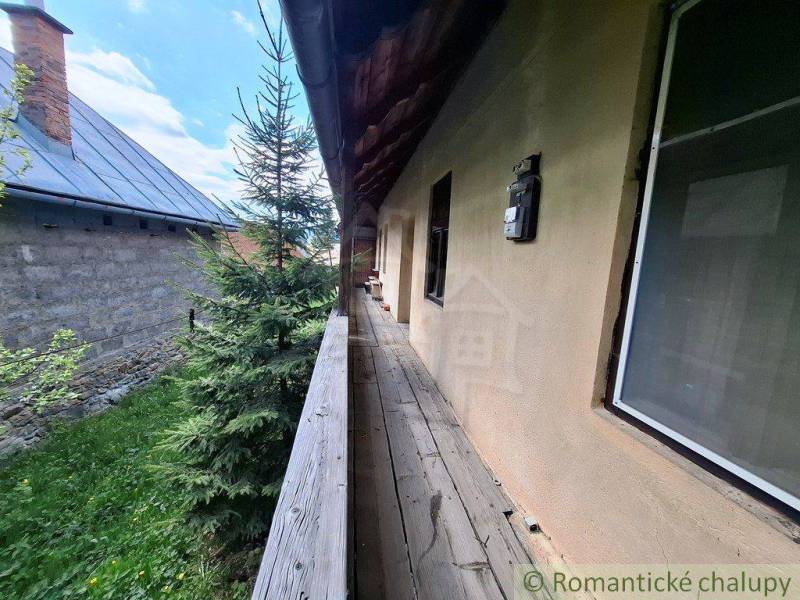 Ein Holzweg neben einem Einfamilienhaus in Pohorelá, umgeben von Grün und einem Nachbargebäude.