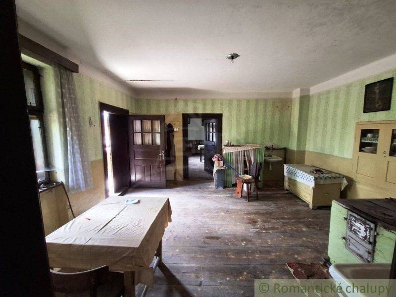 Innenraum eines Einfamilienhauses mit Holzboden, antiken Möbeln und einem einfachen Tisch.